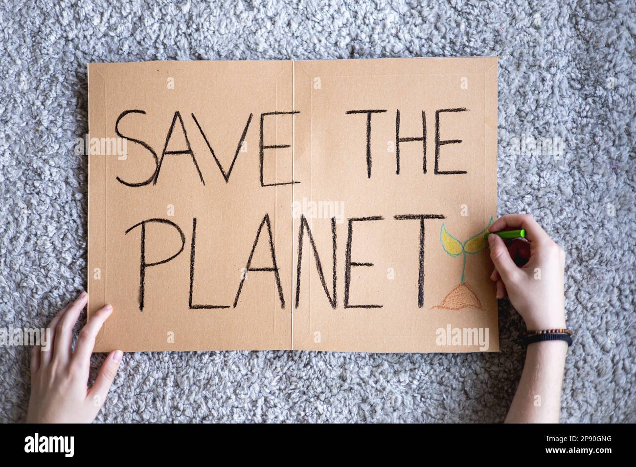 Activist writing 'SAVE THE PLANET' poster for manifestation against global warming and earth pollution. Cardboard banner to protest climate change. Stock Photo