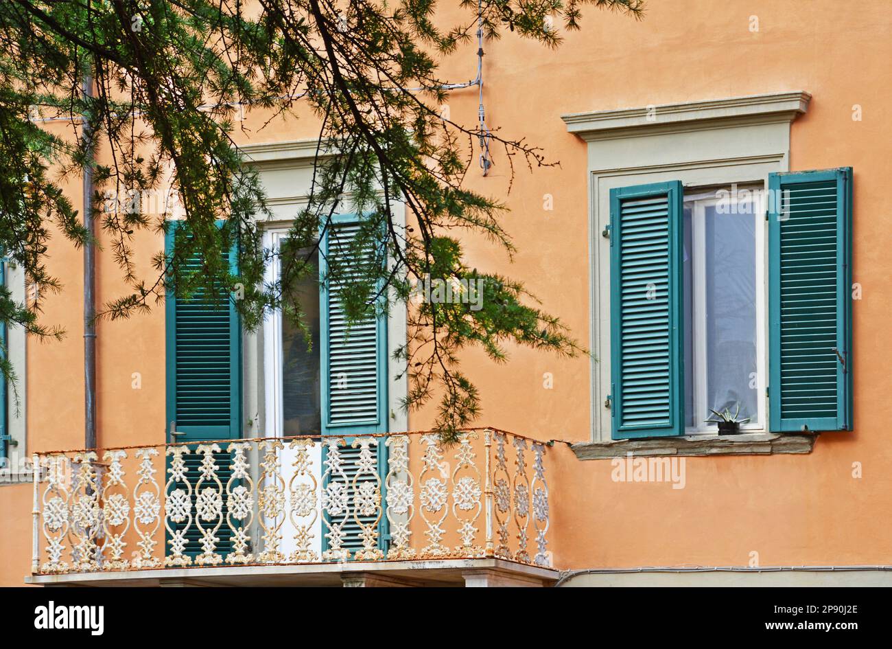 A fragment of the facade of a house with a white openwork metal balcony in square Cavallotti in Pisa, Italy Stock Photo