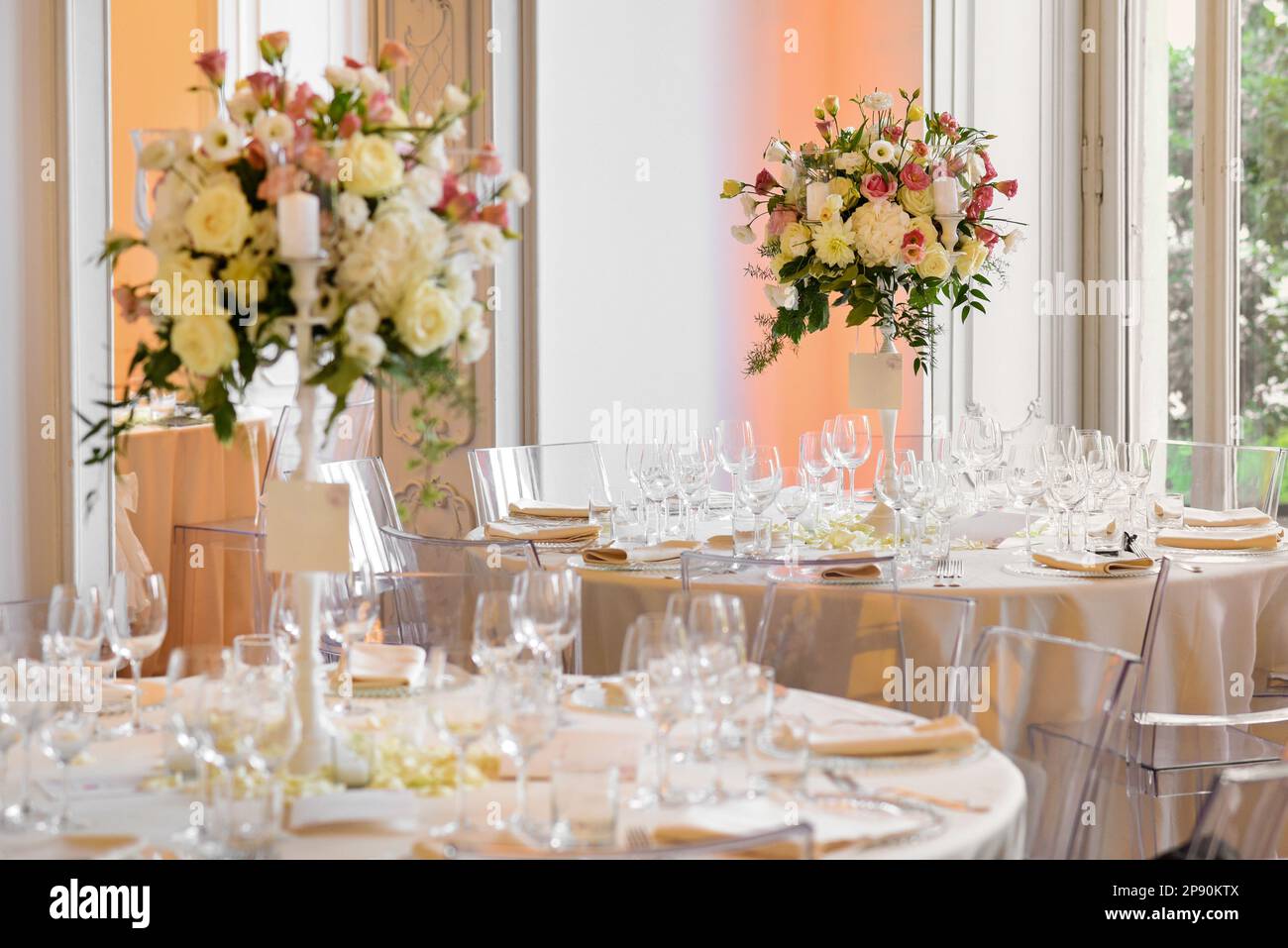 Elegant wedding banquet setting tables with glassware and blooming flowers in vases against window Stock Photo