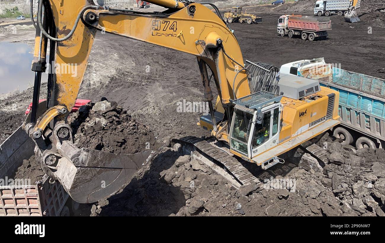 Excavator Working On Huge Mining Site, Loading The Trucks, Trucks Transport The Material. Stock Photo