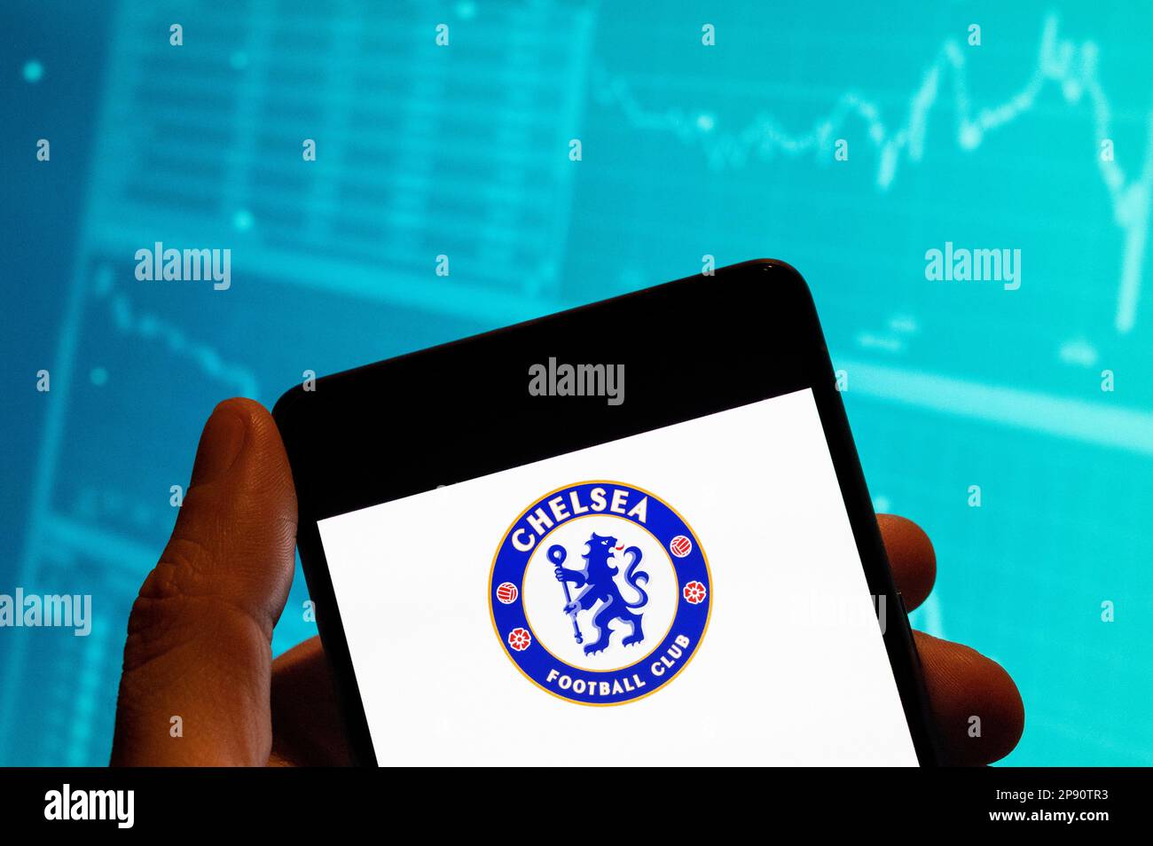 China. 19th Feb, 2023. In this photo illustration, the English professional Premier League football club Chelsea team logo is seen displayed on a smartphone with an economic stock exchange index graph in the background. Credit: SOPA Images Limited/Alamy Live News Stock Photo