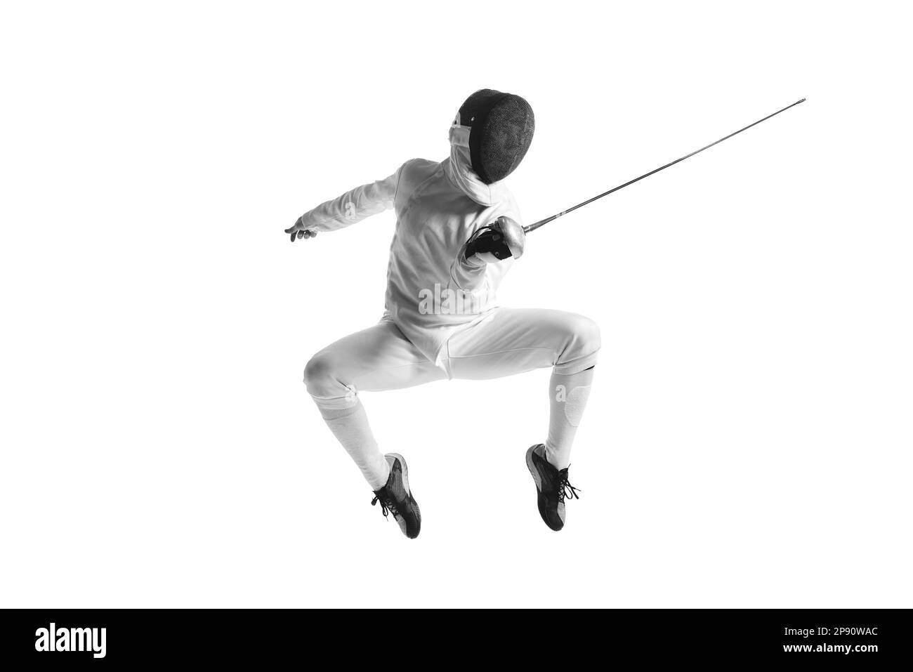 Full-length portrait of sportive man, professional fencer in fencing costume and protective helmet mask in motion isolated on white studio background. Stock Photo
