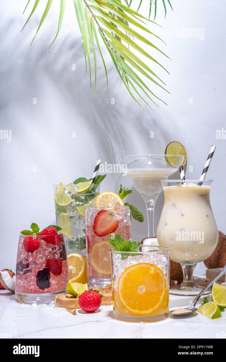 Summer cocktails drinks. Classic alcoholic long drink mocktail versions, various beverages, lemonades with berries, lime, orange, coconut, ice on whit Stock Photo