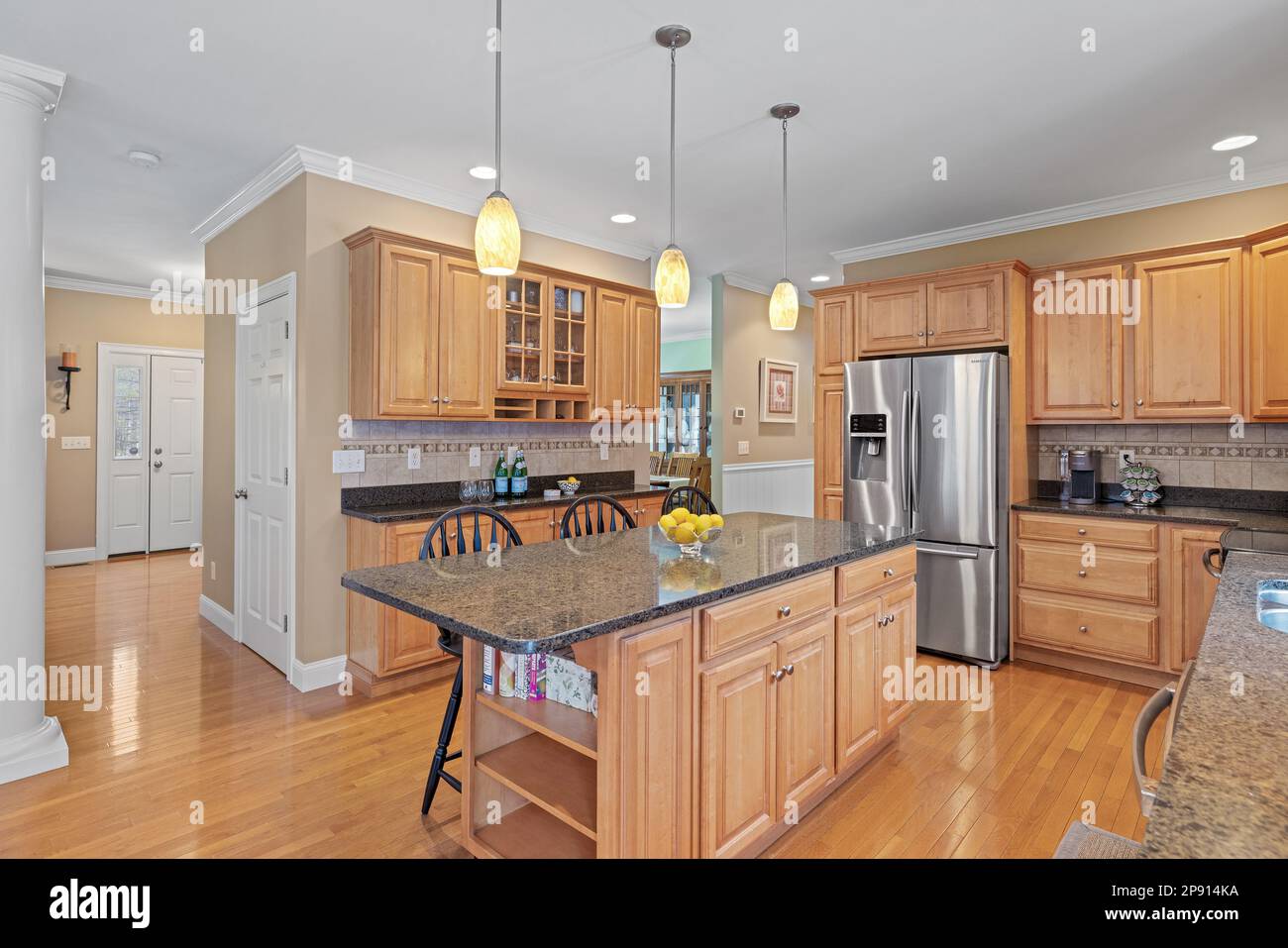 A large kitchen with brown modern furniture and hanging lamps Stock Photo