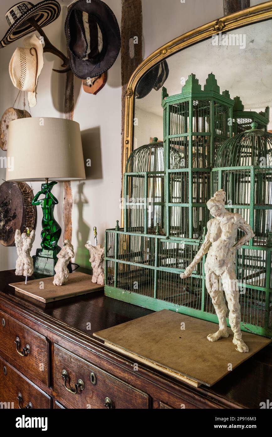 Bird cage and statues on chest of drawers with hats in 16th century Elizabethan manor house, Suffolk, UK Stock Photo