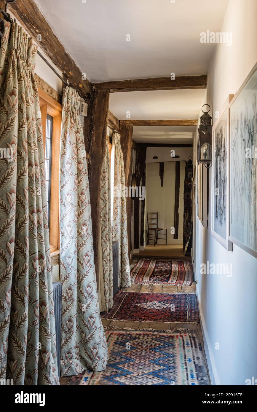 Curtains and patterned rugs in hallway of 16th century Elizabethan manor house, Suffolk, UK Stock Photo