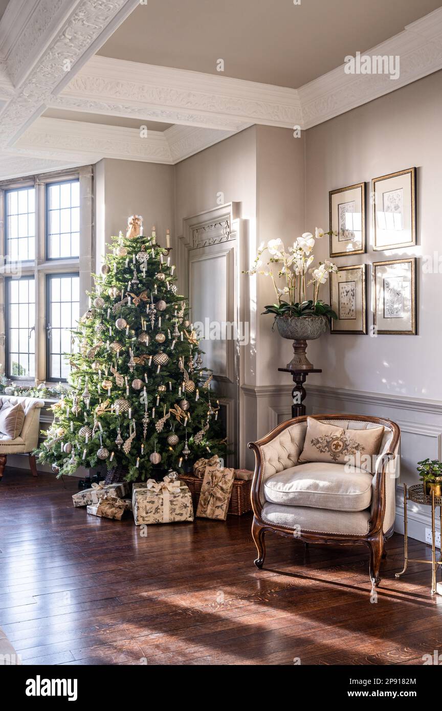 Christmas gifts under tree with armchair in Arts and Crafts style country house, Kent, UK Stock Photo