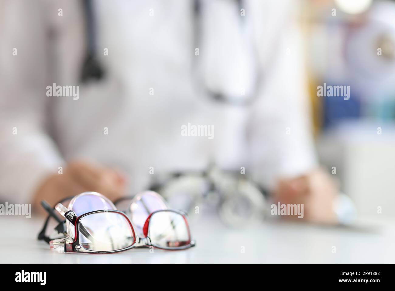 Ophthalmologist sits in background with various glasses for fitting