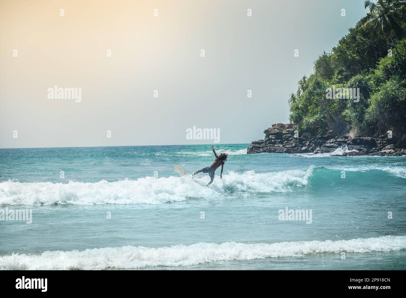 Hiriketiya Beach, Dickwella. Sri Lanka - 16.02.2023. Young guy surfing in ocean. Tropical vacation on Sri Lanka. Stock Photo
