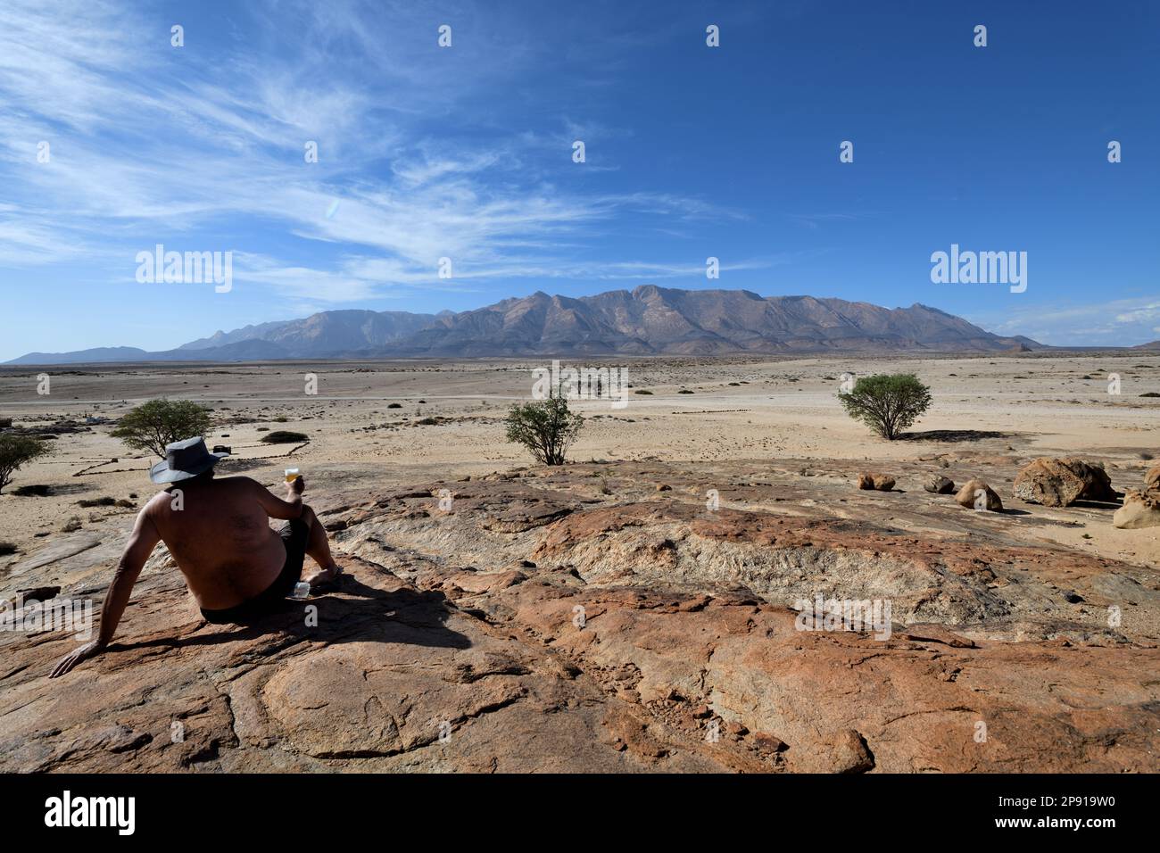 Man with beer looking at Brandberg Mountain, Namibia Stock Photo