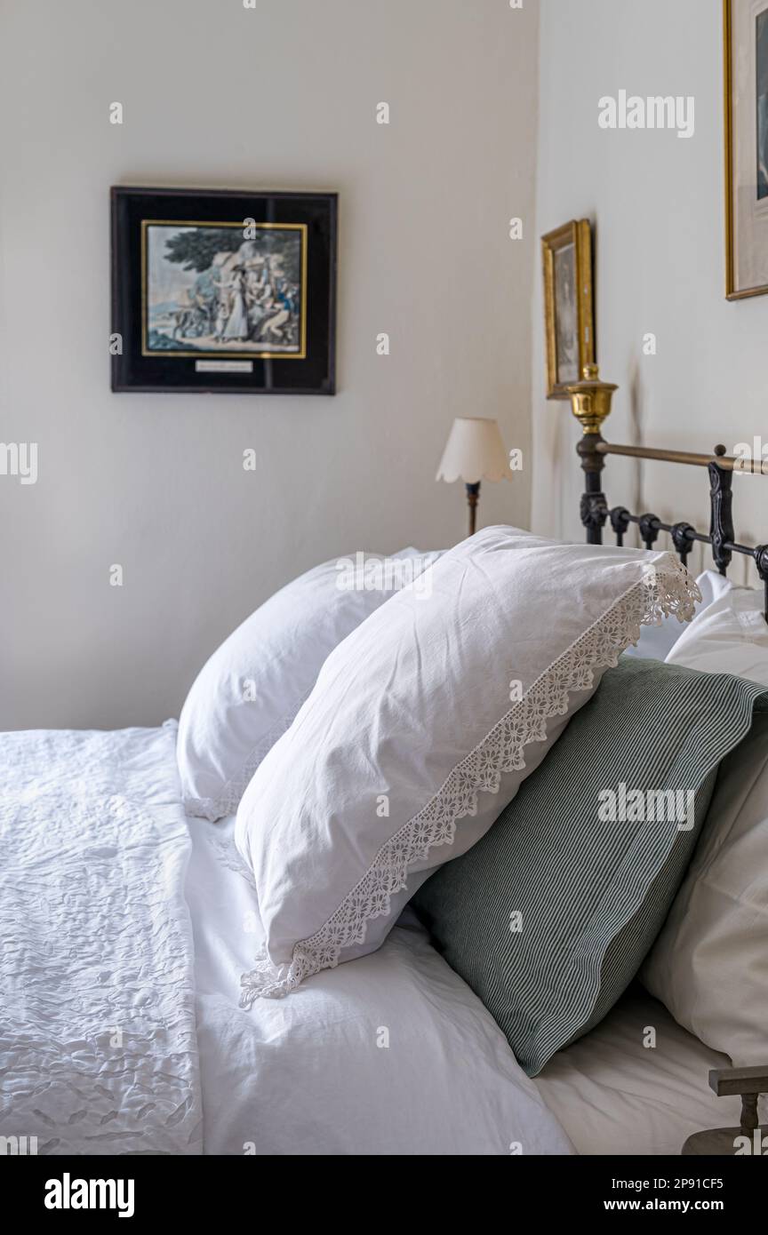 Lace trimmed pillows and artwork in bedroom of 19th century Norfolk cottage, UK Stock Photo