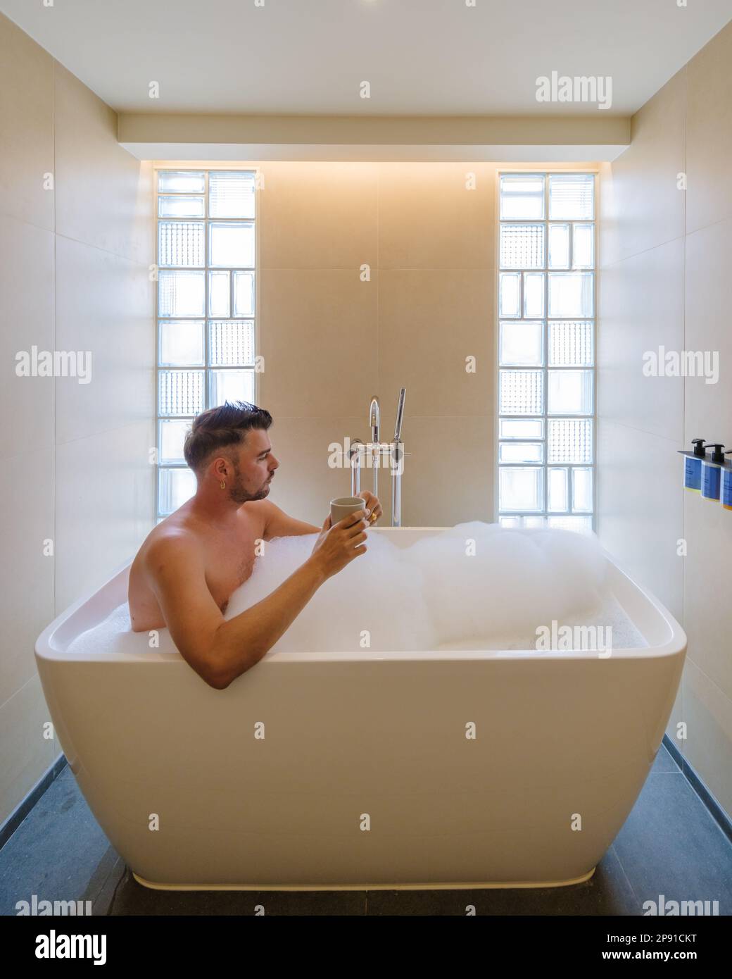 young men in white bathtub in a luxury hotel room, classic bathroom