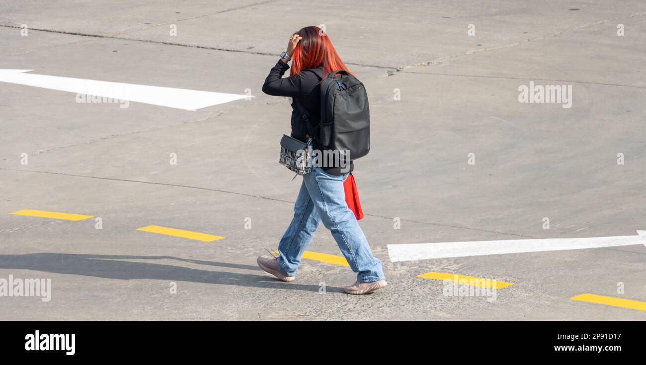 A woman with red hair walks down the street Stock Photo - Alamy