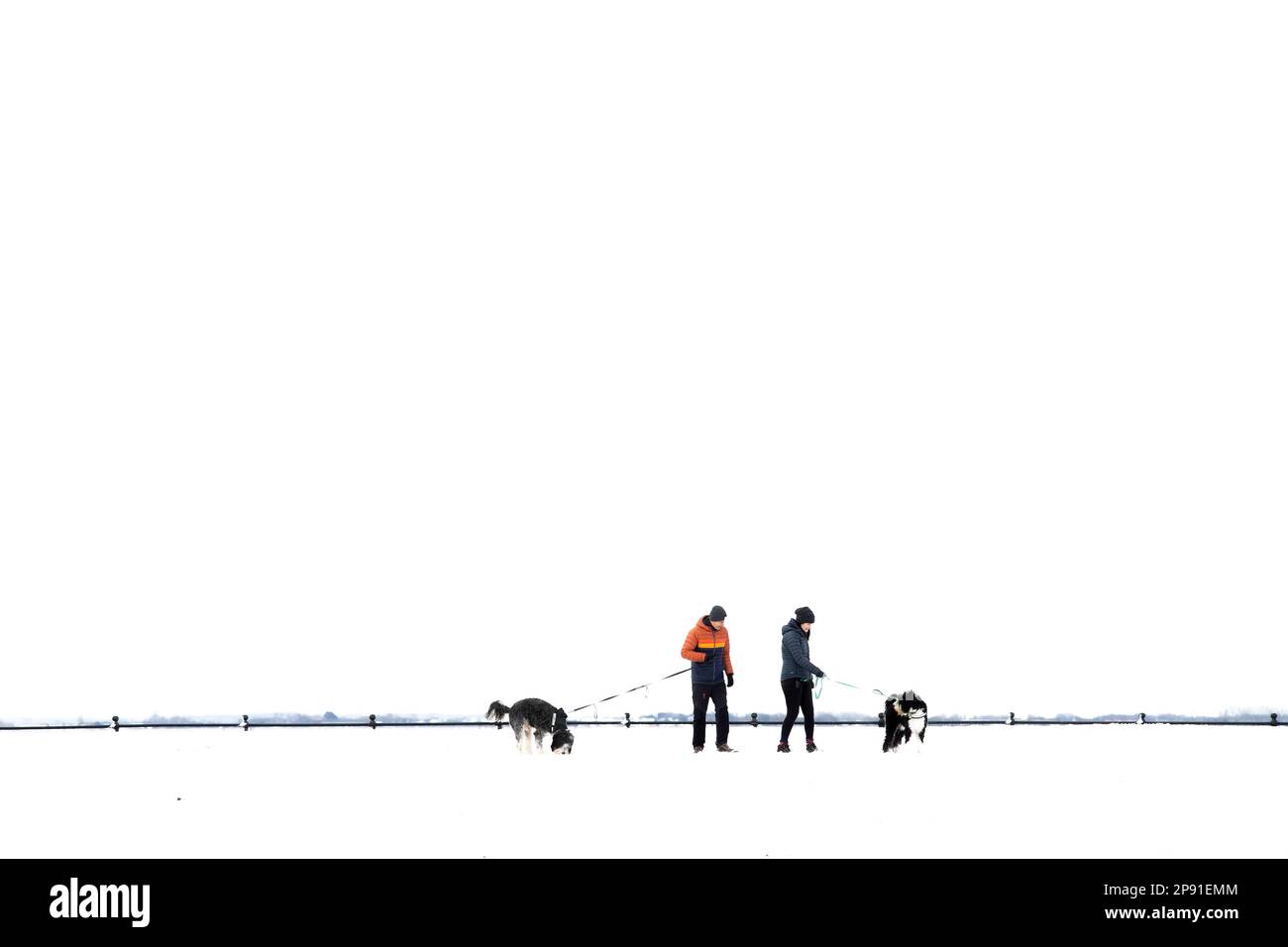 Lytham, UK. A man and woman walking their dogs in the snow. 10th March, 2023. Credit: Tim Markland/Alamy Live News. Stock Photo