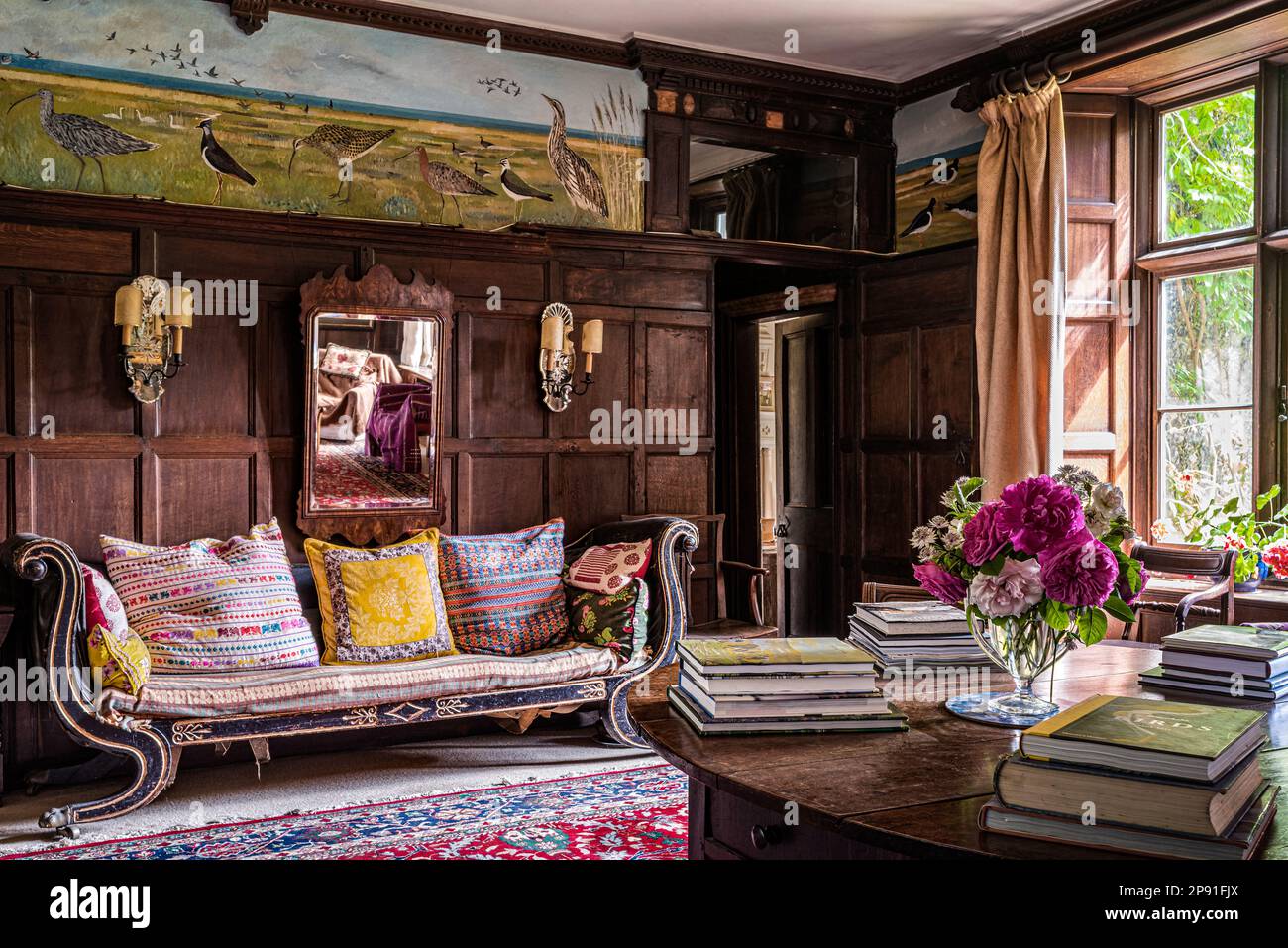 Regency sofa in Edwardian panelled hall with local birdlife freize by Anabel Grey. Wiveton Hall 17th century Jacobean manor house, Norfolk, UK Stock Photo
