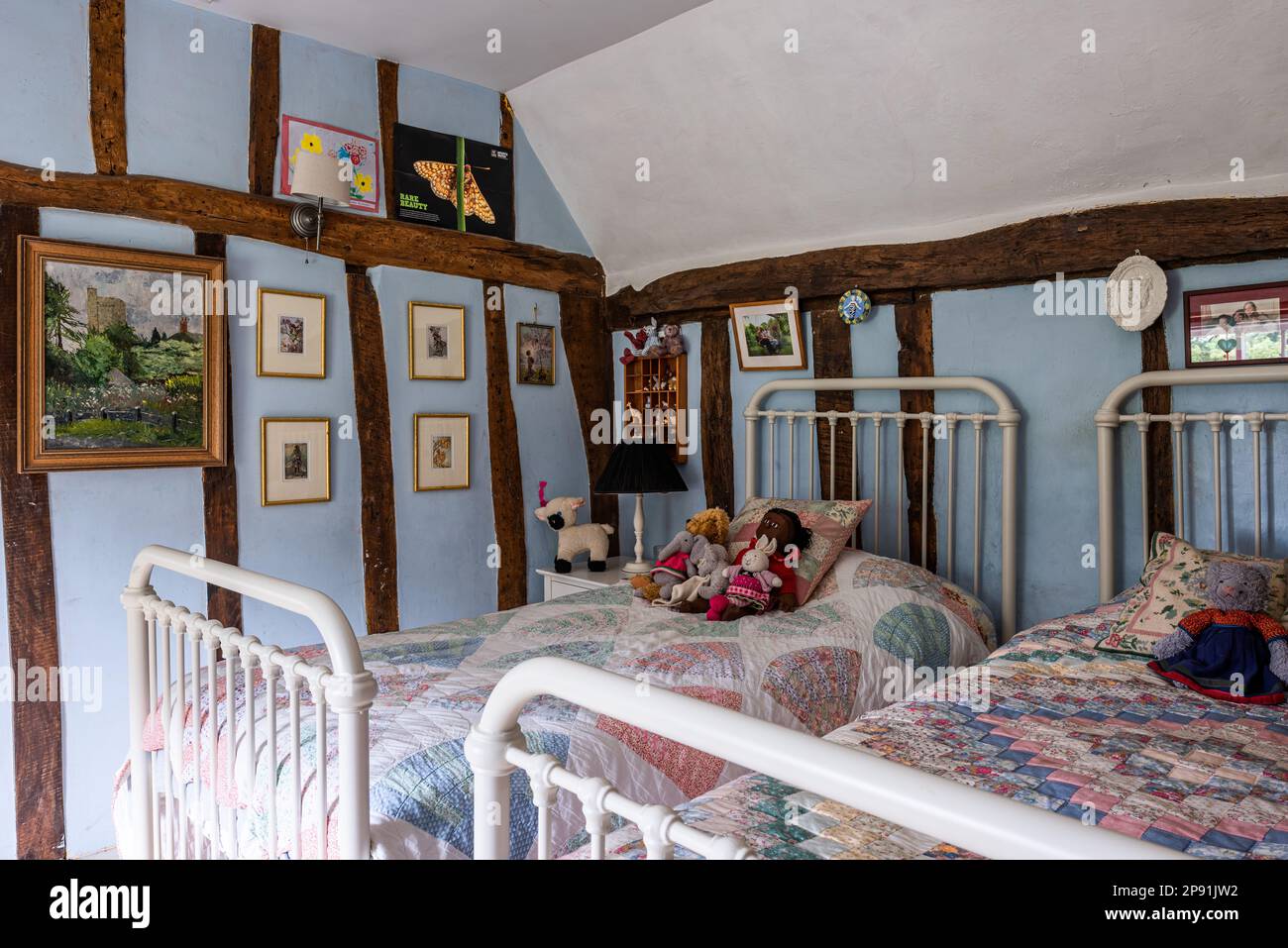 Soft toys on patchwork quilt in twin bedroom of 16th century Tudor farmhouse, Suffolk, UK. Stock Photo