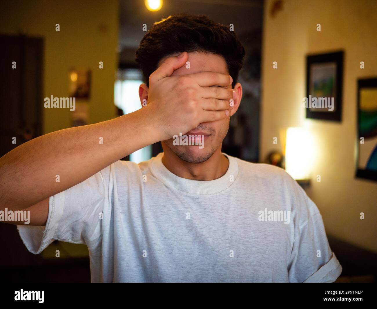 Young man covering eyes with his hand Stock Photo - Alamy