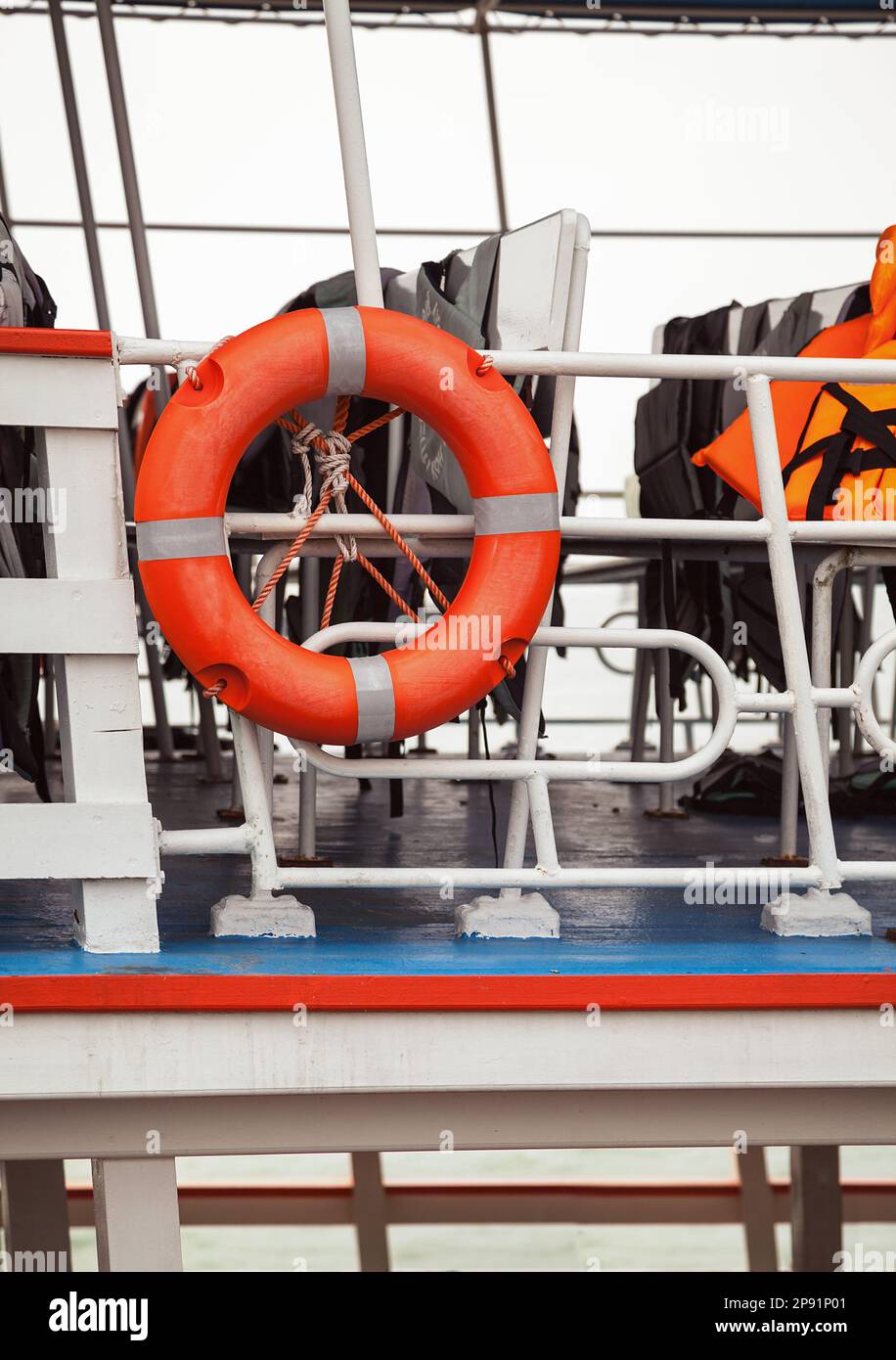 Lifebuoy and life jackets on a ferry deck close-up. Rescue equipment on a ship: buoy and vests for emergencies Stock Photo