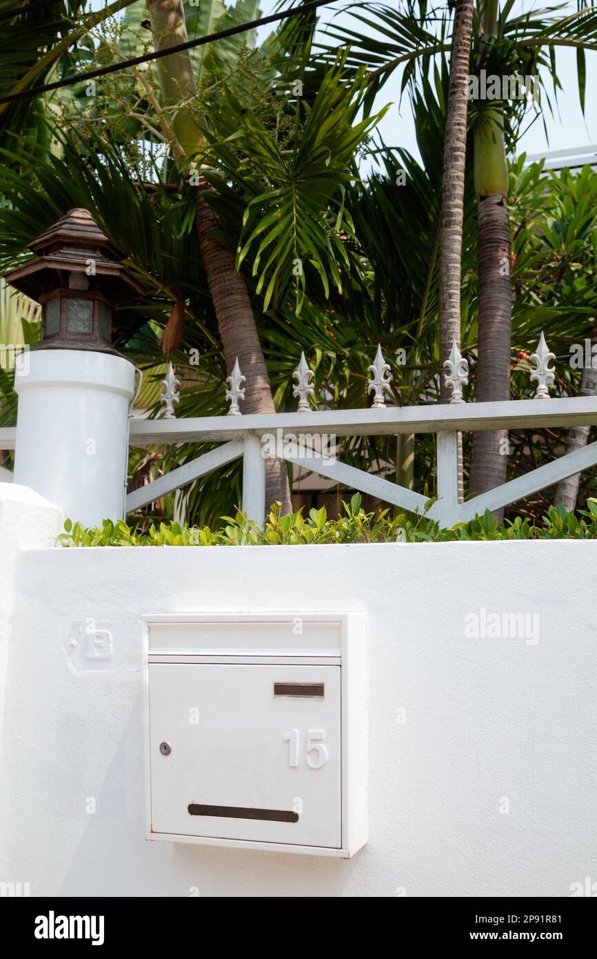 House mailbox mounted on a white villa fence. Postbox hanging on a wall