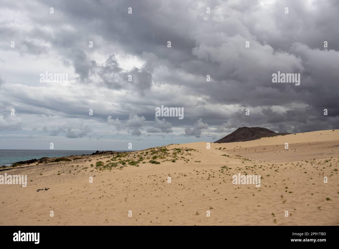 Unique european desert as a part of natural park. Stormy clouds above the sand dunes in the winter season. Dark tones of the Atlantic ocean. Corralejo Stock Photo