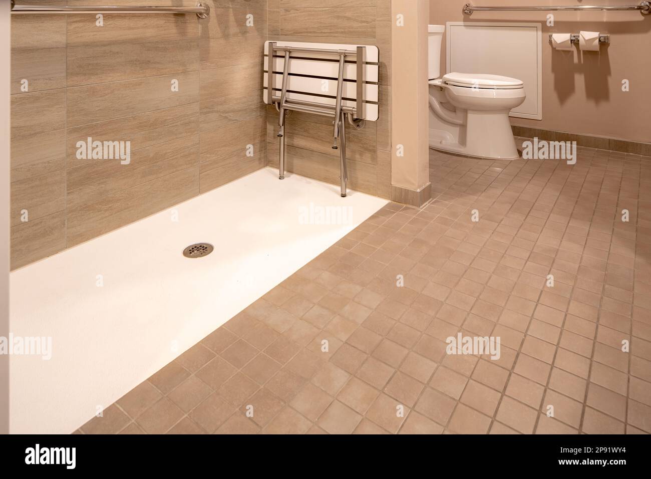 Wheelchair accessible hotel bathroom shower with tile floor and walls. Stock Photo