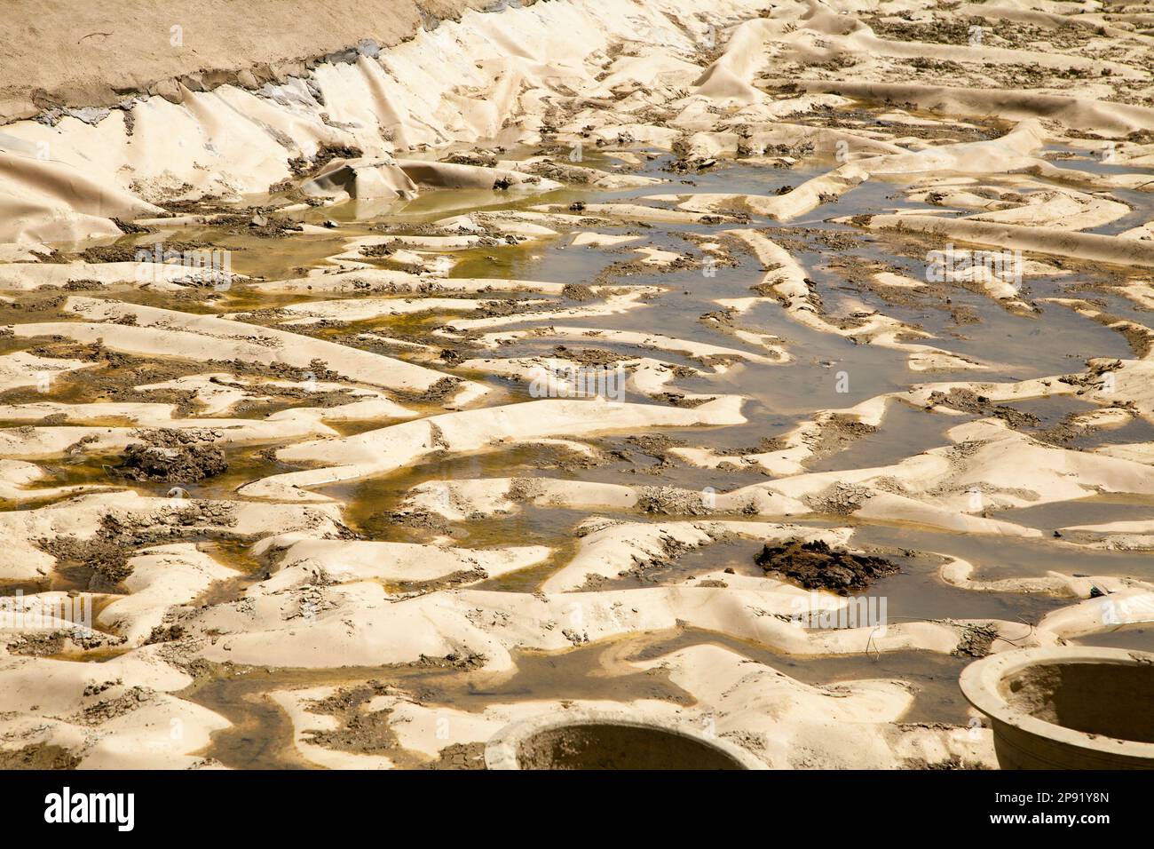 Dirty liner at a bottom of a drained pond. The process of building an artificial lake. Abstract dirty industrial background Stock Photo