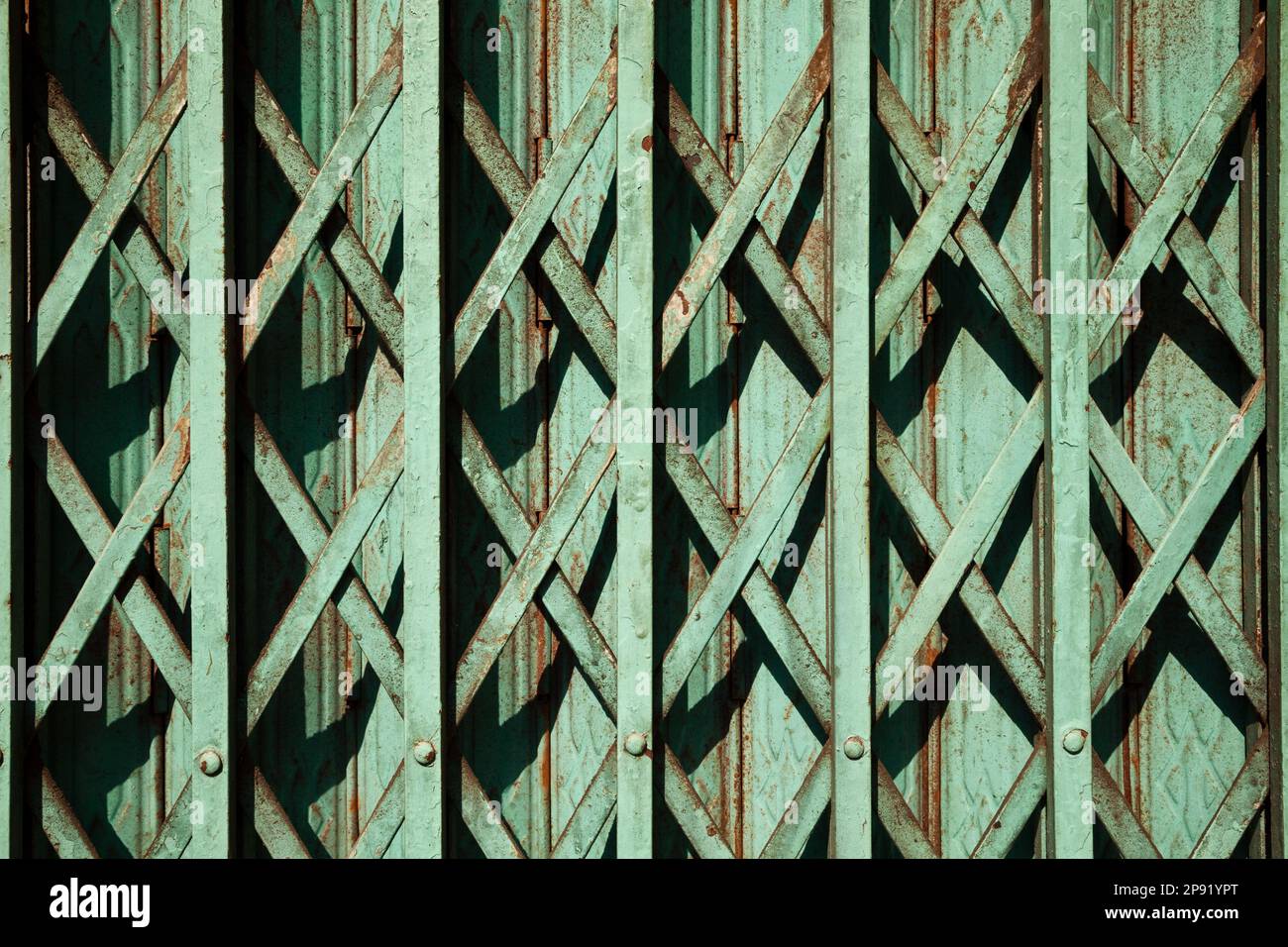 Teal color old rusty folding gate background. Green geometric pattern lattice on a store entrance. Closed Asian shop detail Stock Photo