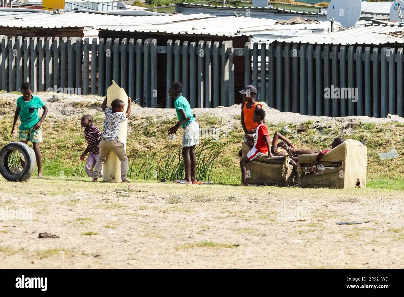 a group of South African black young children playing on the perimeter of a housing township concept authentic daily life Stock Photo