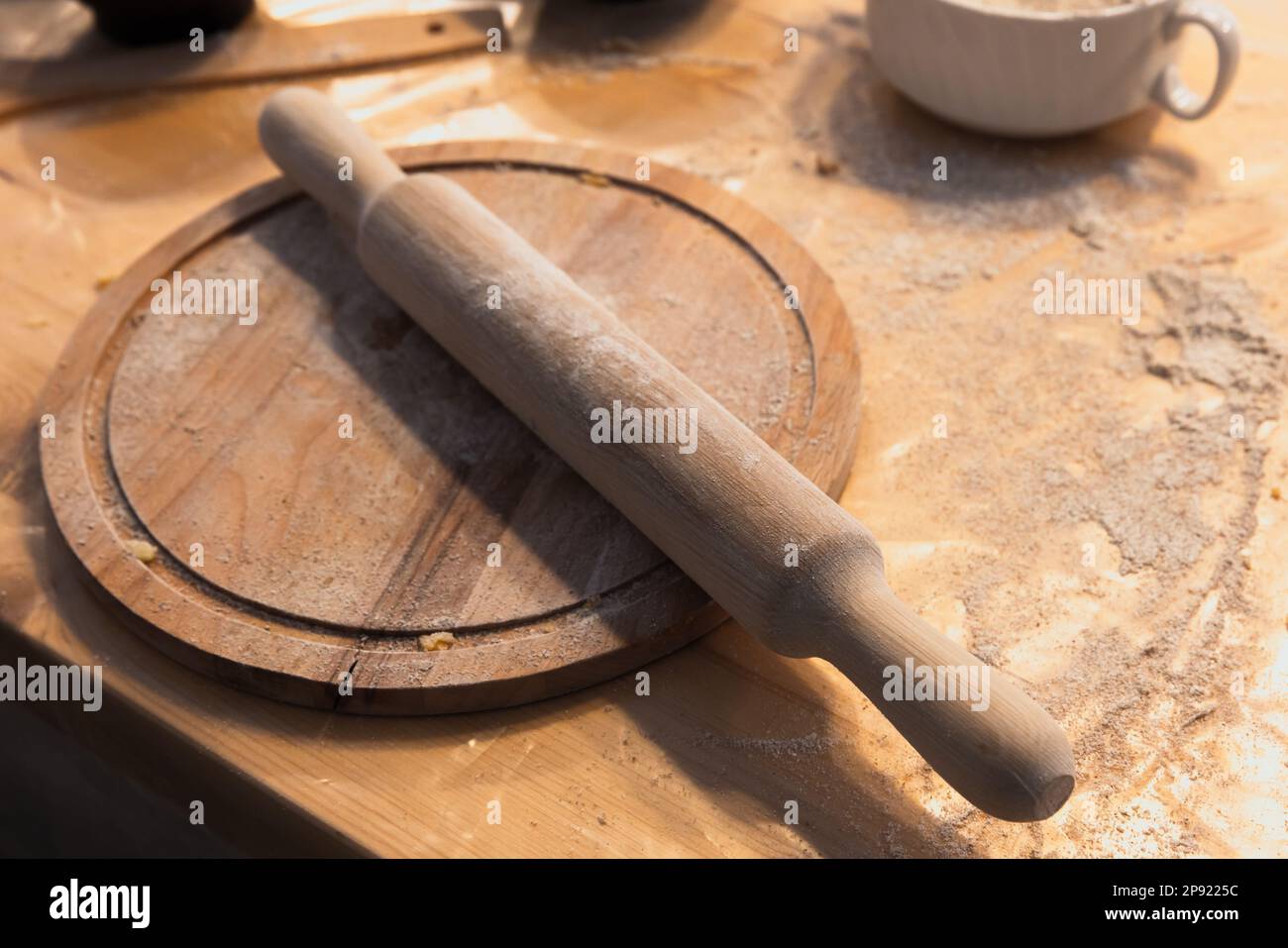 Wooden rolling pin is on a round plate, bakery equipment close up photo with selective soft focus Stock Photo