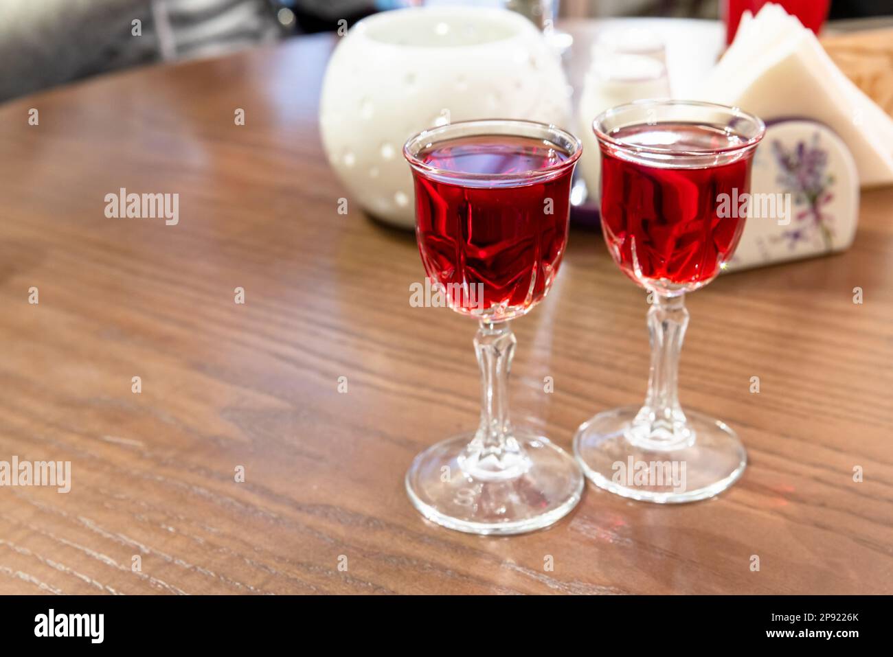 Two glasses of cranberry tincture stand on the wooden table, close up photo with selective soft focus Stock Photo
