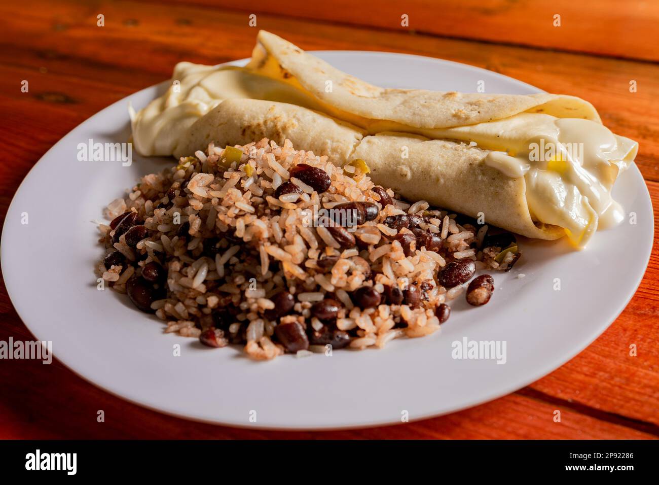 Traditional gallo pinto with Quesillo served on wooden table. Nicaraguan gallopinto with quesillo on the table. typical nicaraguan foods Stock Photo