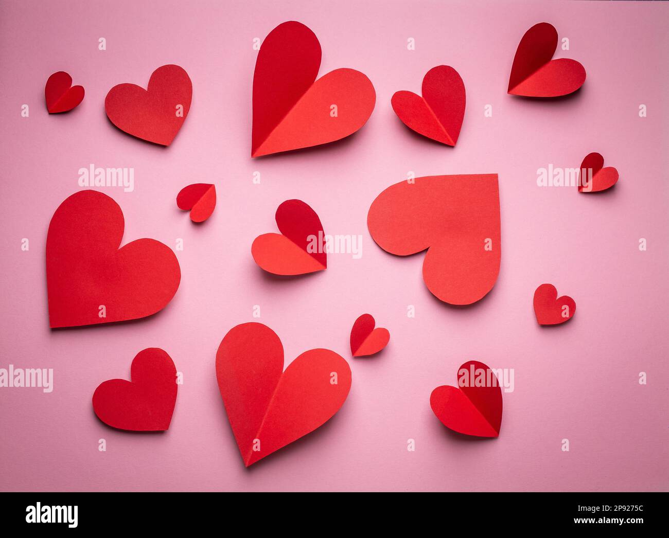 Red hearts cut from paper on pink background, paper craft origami style ...