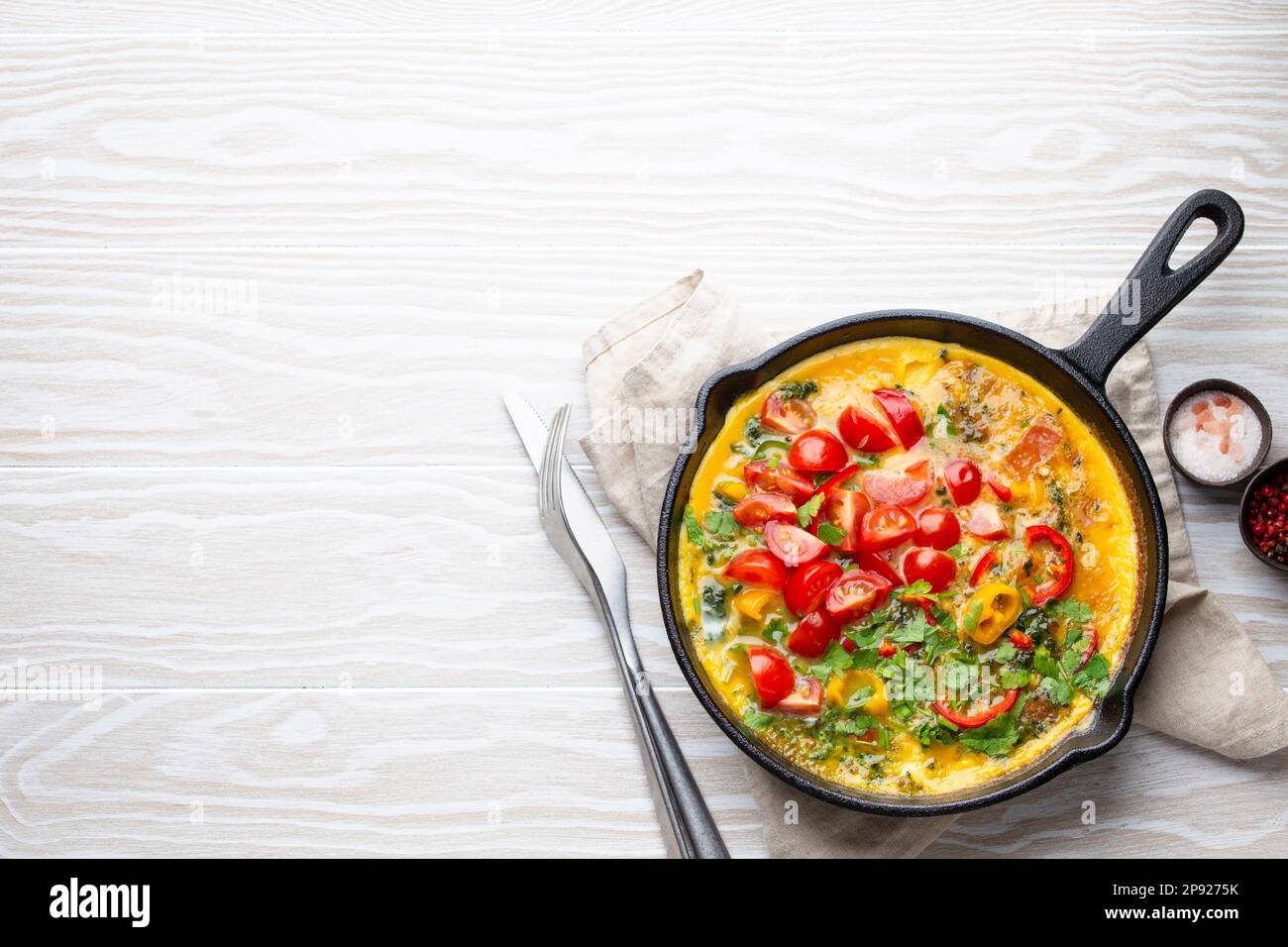 Healthy frittata in cast iron pan with fried beaten eggs and seasonal