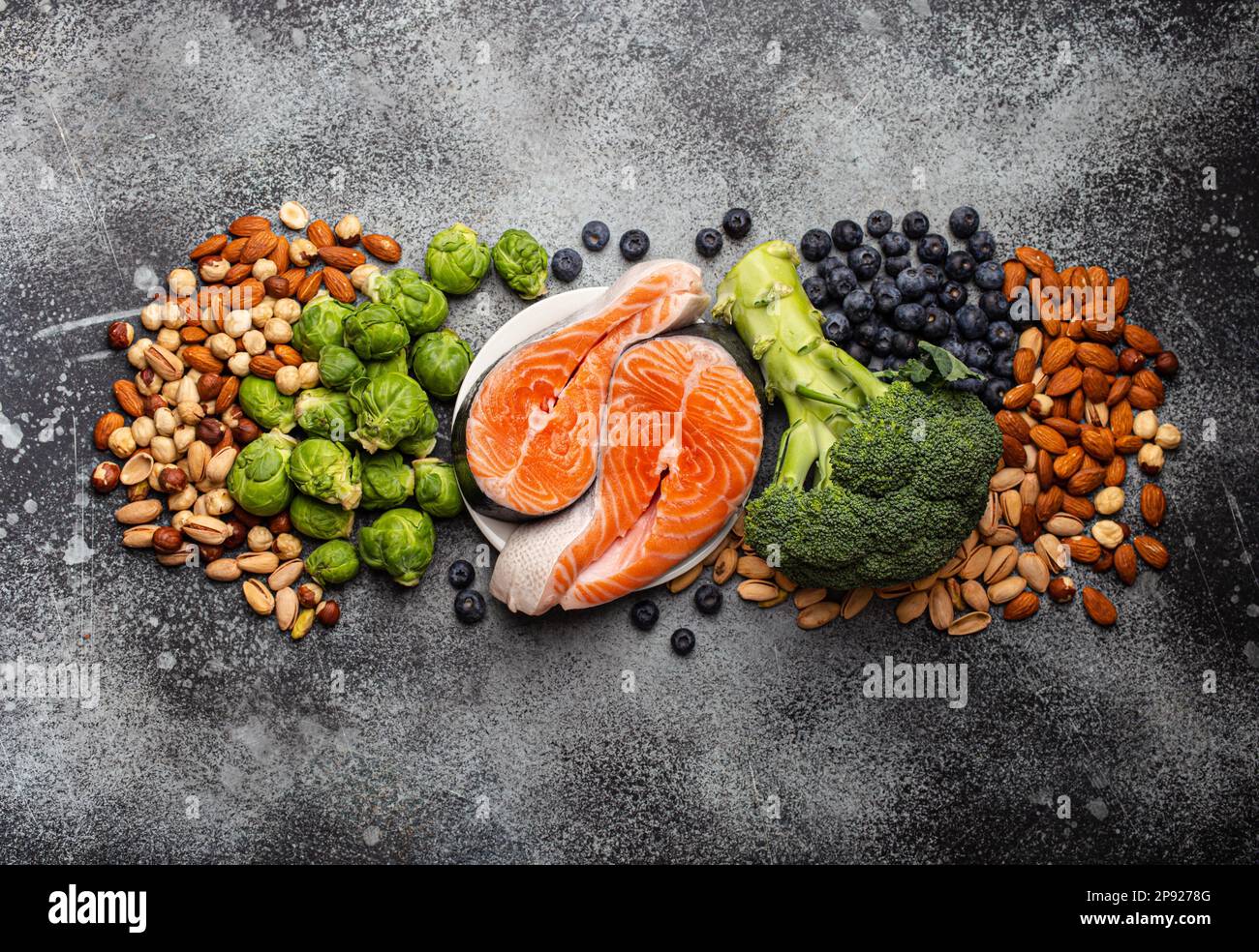 Assorted food for brain health and good memory: fresh salmon, vegetables, nuts, berries on stone background. Healthy fresh products to boost brain Stock Photo
