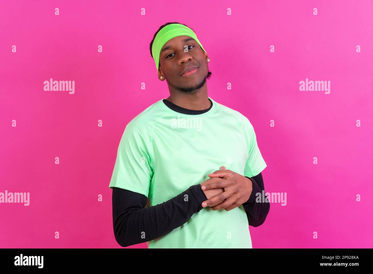 Black ethnic man in green clothes on a pink background, concept portrait Stock Photo