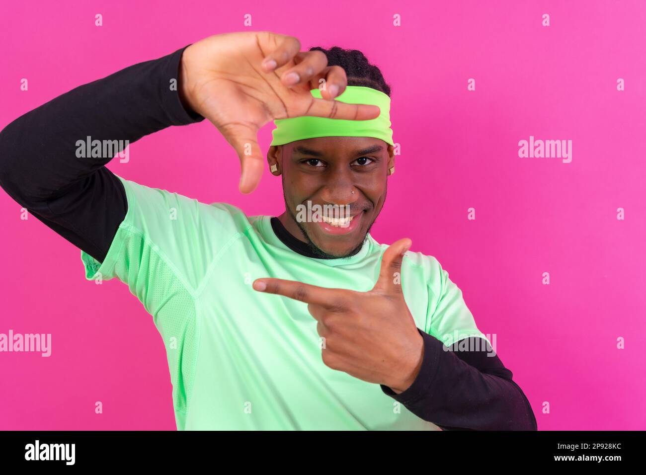 Black ethnic man in green clothes on a pink background, concept portrait, gesture smiling Stock Photo