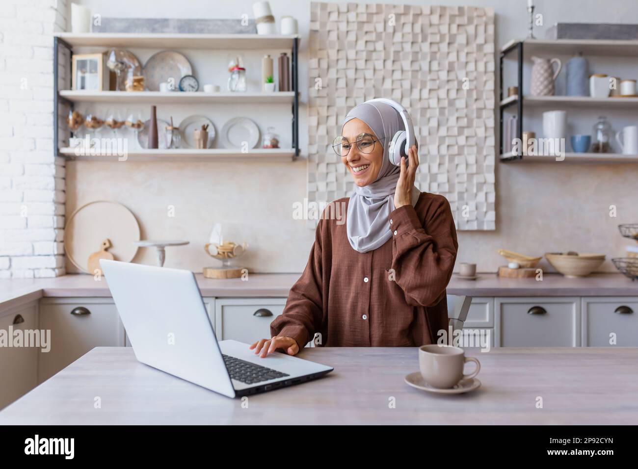 Young beautiful Muslim student woman in hijab sitting at home in ...