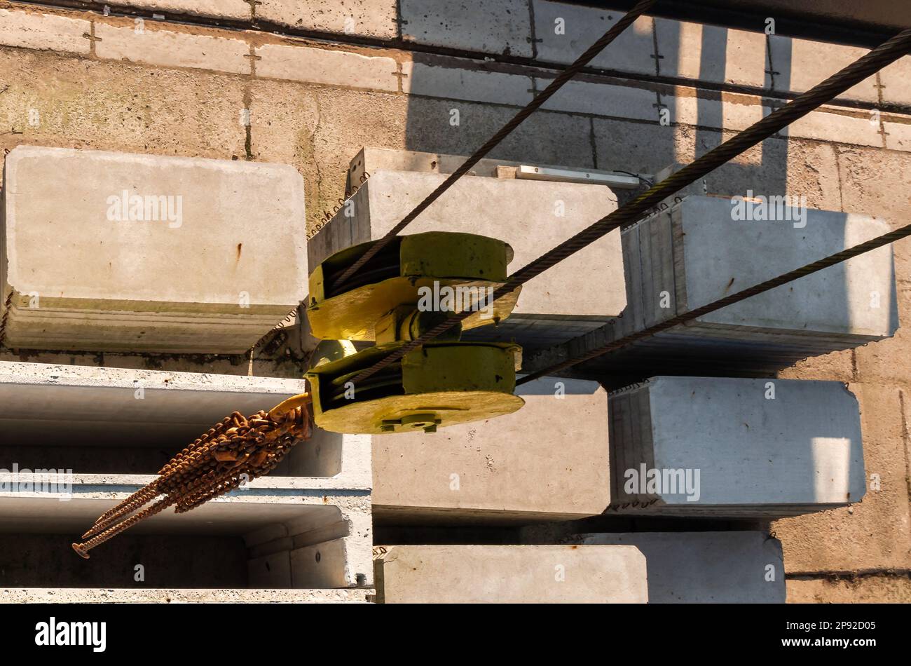 Factory overhead crane hook and chain, suspended over concrete slabs Stock Photo
