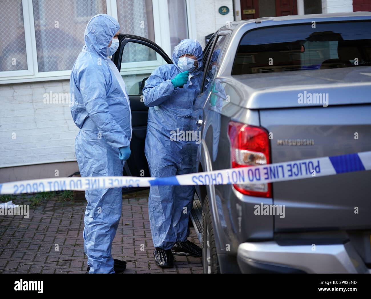 Police forensics officers examine a vehicle outside a property on ...