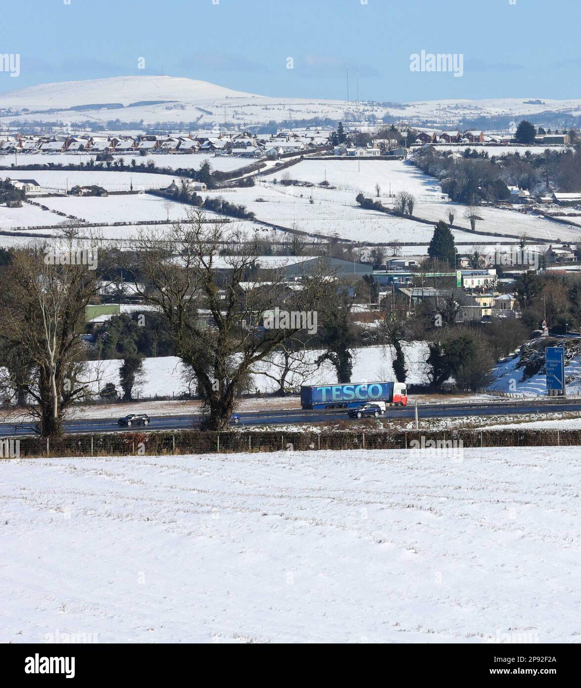 Moira, County Down, Northern Ireland, UK. 10 Mar 2023. UK weather - a bright sunny day with blue sky after a lot of overnight snow. Snow in the surrounding countryside viewed from Moira Demesne with traffic moving along the M1 motorway in Northern Ireland. Credit: CAZIMB/Alamy Live News. Stock Photo