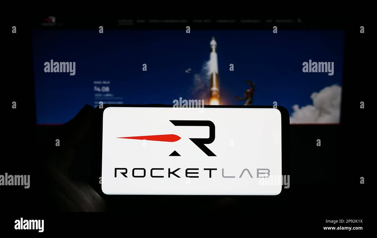 Person holding smartphone with logo of aerospace company Rocket Lab USA Inc. on screen in front