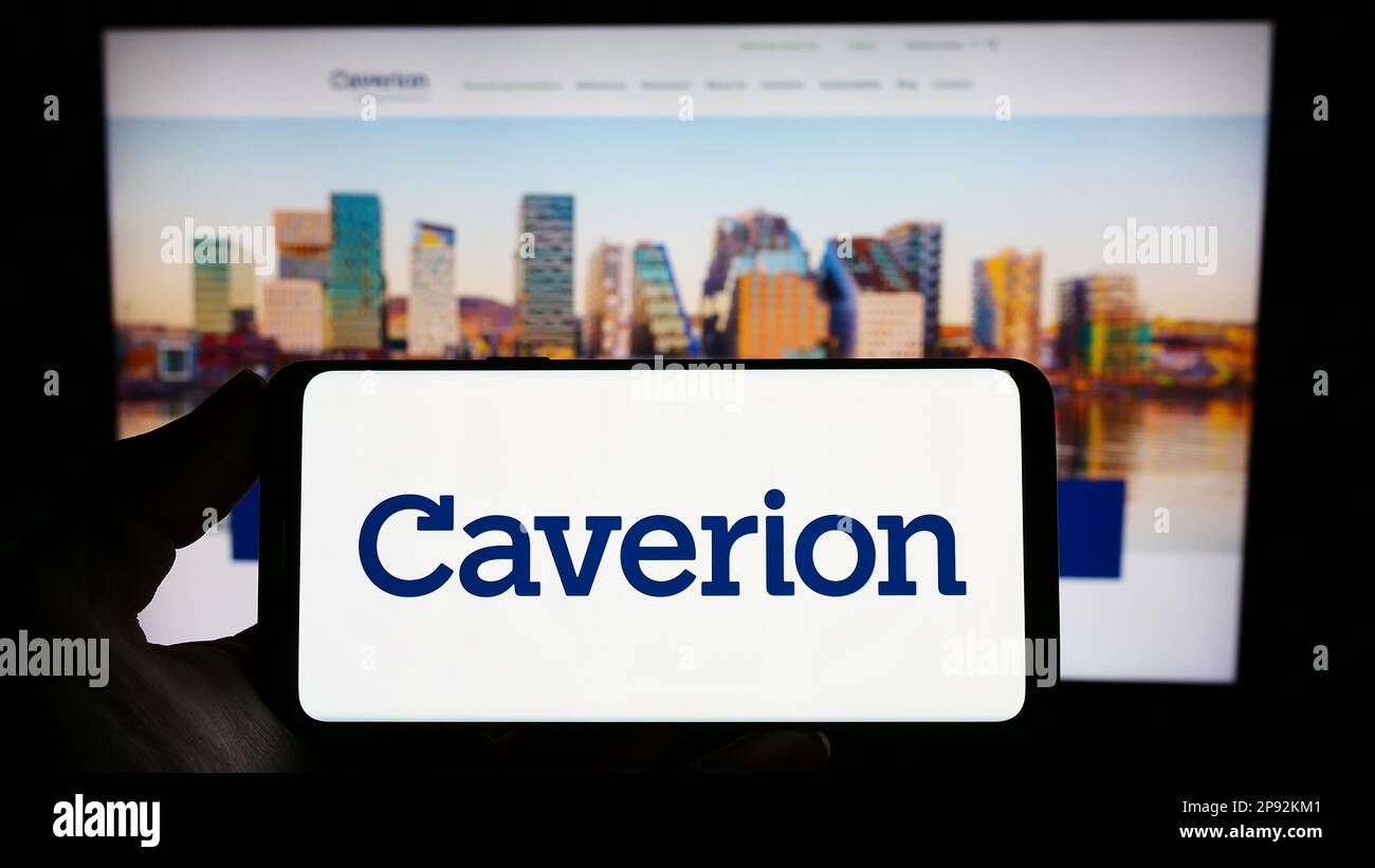 Person holding smartphone with logo of building technology company Caverion Oyj on screen in front of website. Focus on phone display. Stock Photo