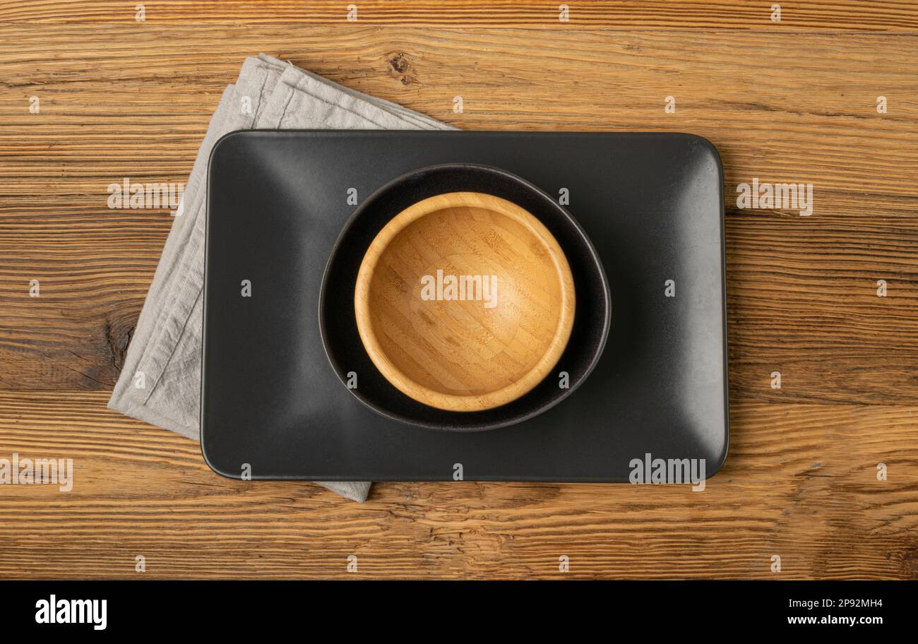 Empty Black Bowls and Wood Plates on Wooden Table Background, Black Plate Mockup Top View