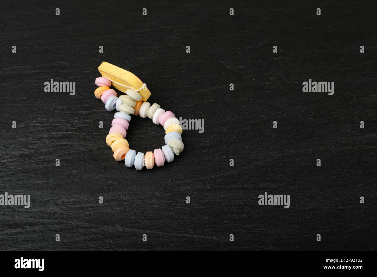 Tablet Candies Bracelet, Compressed Sugar Powder Confectionery, Dextrose Candy Necklace Parts, Lozenges on Black Background Stock Photo