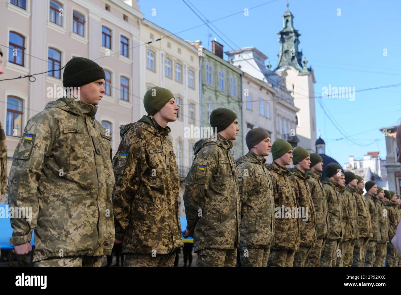 Lviv, Ukraine. 10th Mar, 2023. Military personnel sing the national anthem while holding a huge Ukrainian flag in front of the city hall Ratusha in honor of the anniversary of the first performance of the national anthem 158 years ago. (Photo by Mykola Tys/SOPA Images/Sipa USA) Credit: Sipa USA/Alamy Live News Stock Photo