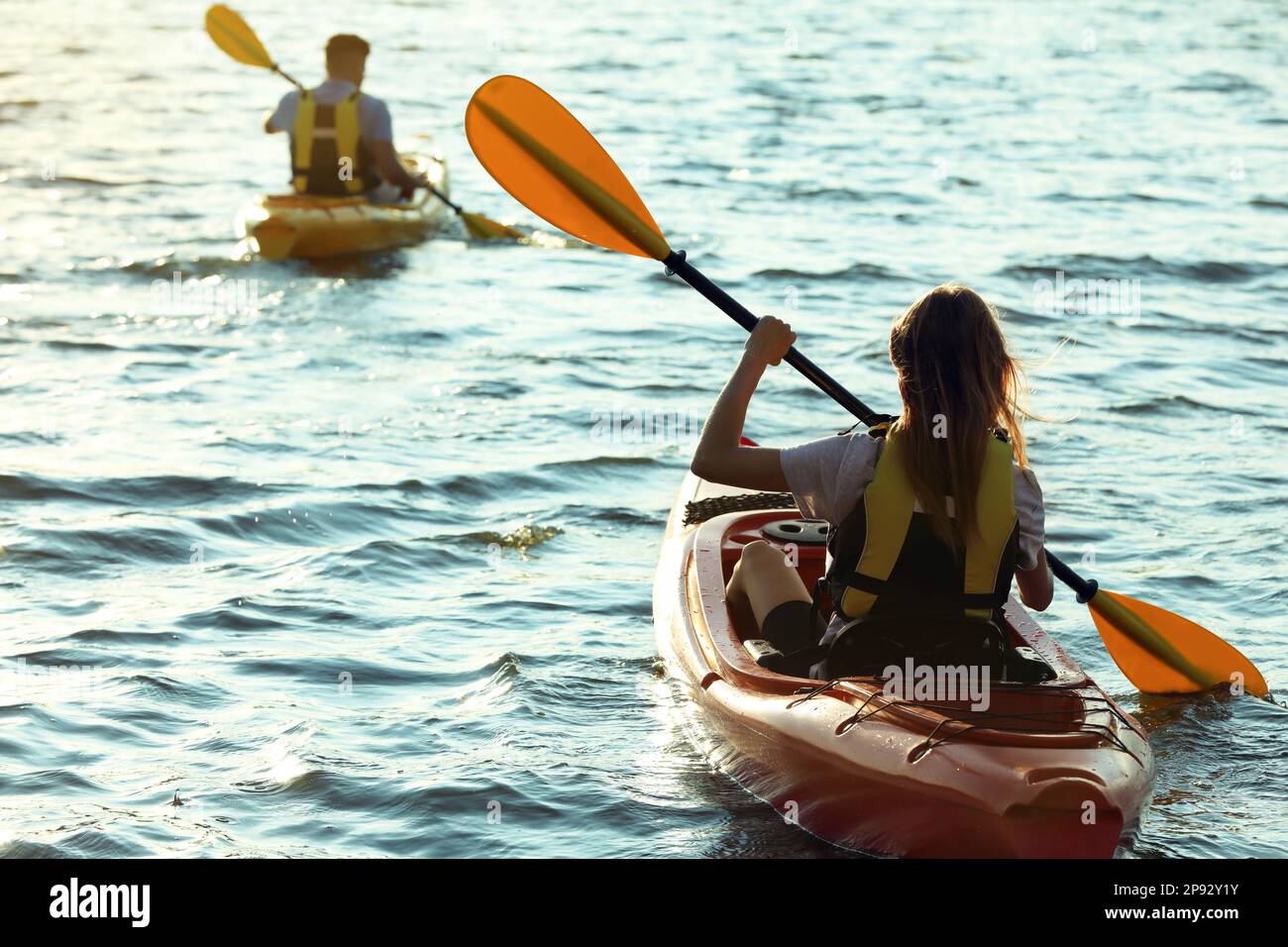 Couple in life jackets kayaking on river, back view. Summer activity