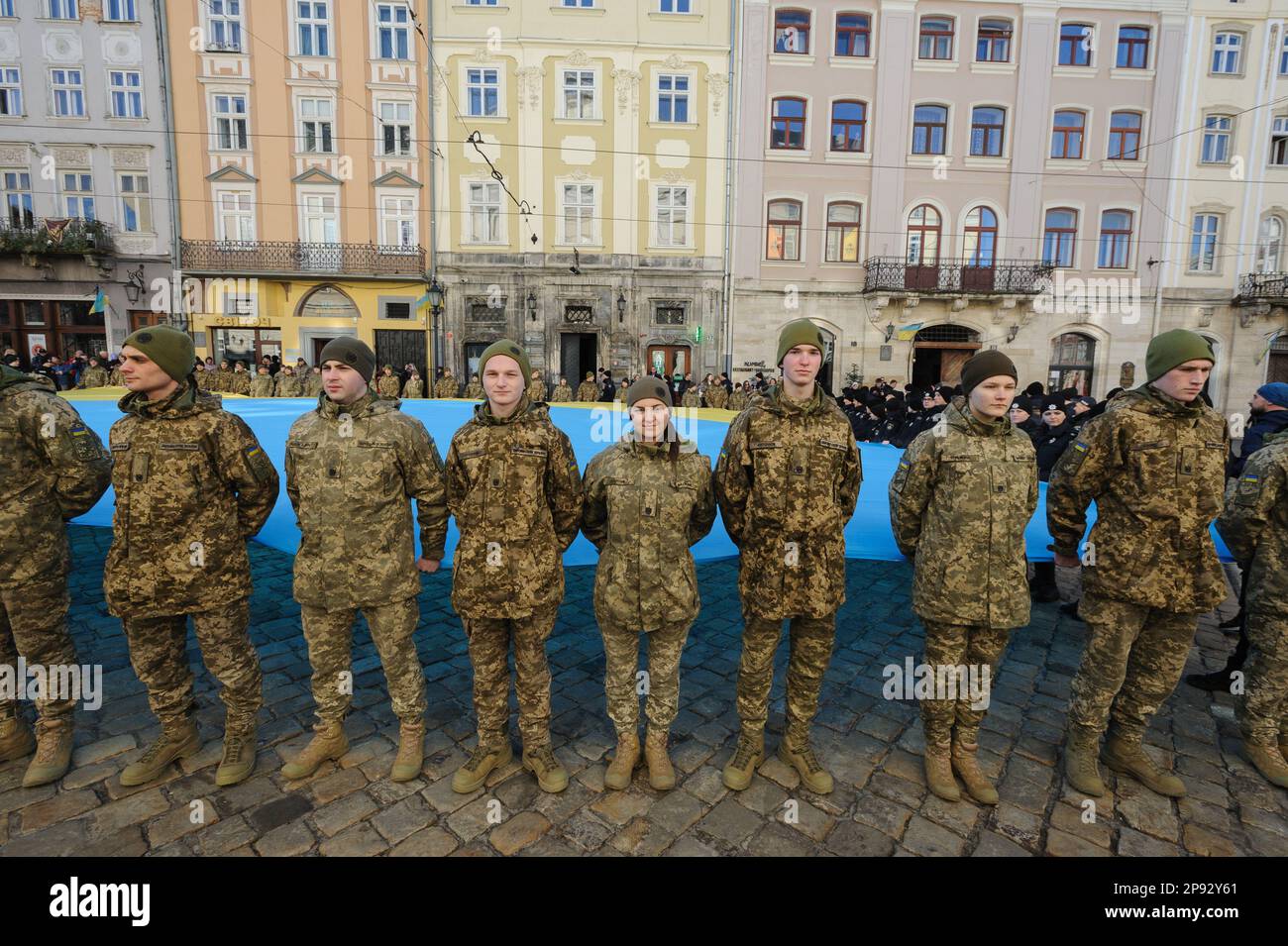 Lviv, Ukraine. 10th Mar, 2023. Military personnel sing the national anthem while holding a huge Ukrainian flag in front of the city hall Ratusha in honor of the anniversary of the first performance of the national anthem 158 years ago. (Photo by Mykola Tys/SOPA Images/Sipa USA) Credit: Sipa USA/Alamy Live News Stock Photo