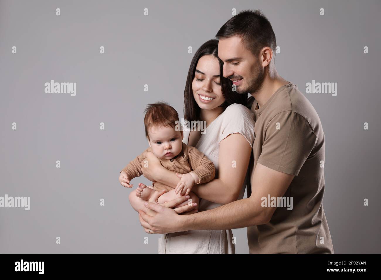 Happy family. Couple with their cute baby on grey background ...