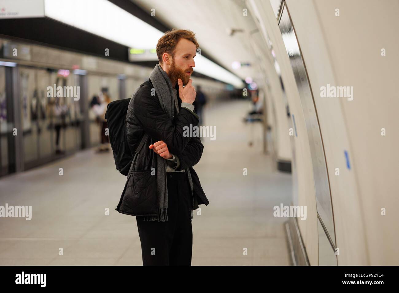 Thoughtful man looking at subway train traffic map at station Stock Photo