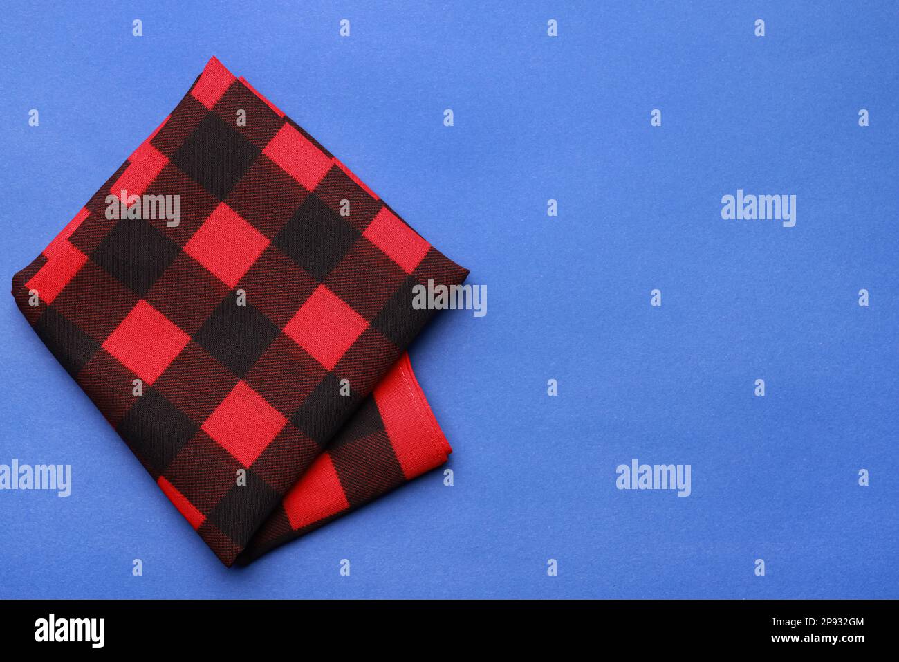 Folded red bandana with check pattern on blue background, top view. Space for text Stock Photo